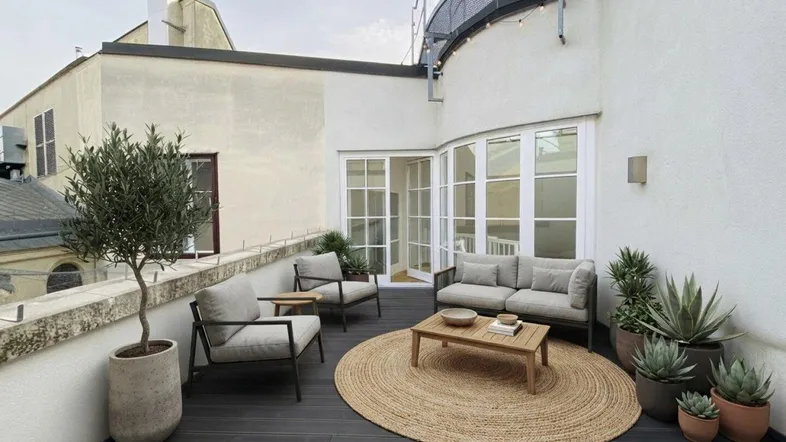 Moderne Dachterrasse mit bequemen Loungemöbeln, Pflanzen und Blick auf die umliegenden Gebäude.