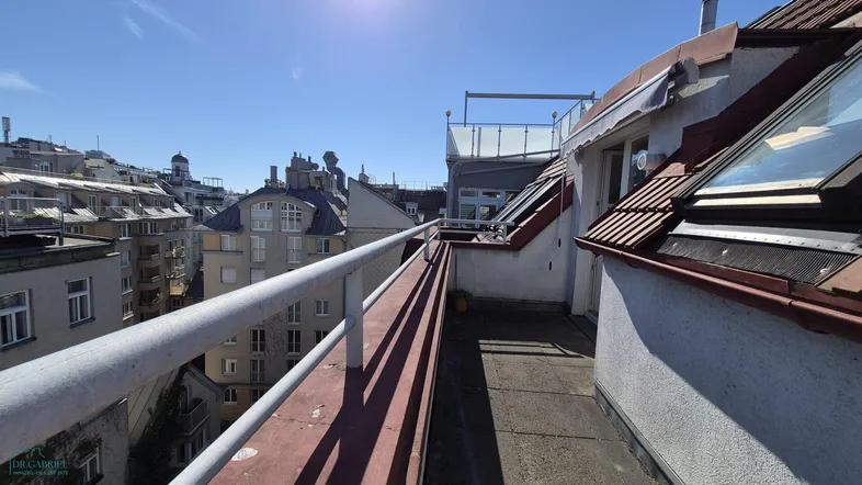 Dachterrasse mit weitem Blick über die Stadt und umliegende Gebäude unter blauem Himmel.