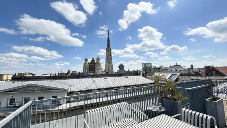Dachterrasse mit Sitzgelegenheiten und Panoramablick über die Stadt, inklusive Stephansdom.