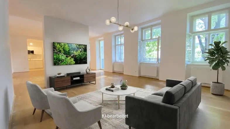 Helles Wohnzimmer mit Parkettboden, hohen Decken und großen Fenstern, offen zu einem Küchenbereich.