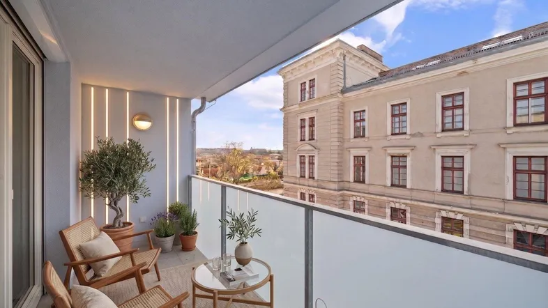 Moderner Balkon mit Sitzgelegenheiten und Blick auf ein historisches Gebäude.