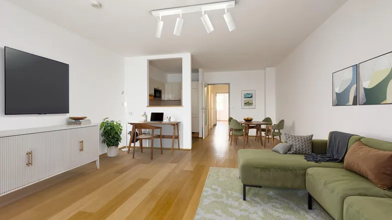 Helles, offenes Wohnzimmer mit Holzboden, moderner Einrichtung und Essbereich im Hintergrund.