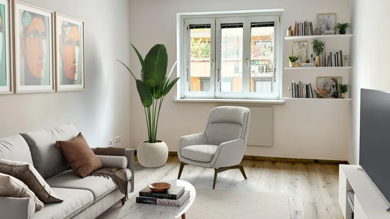 Helles Wohnzimmer mit modernem Sofa, Sessel, Holzboden und Blick nach draußen.
