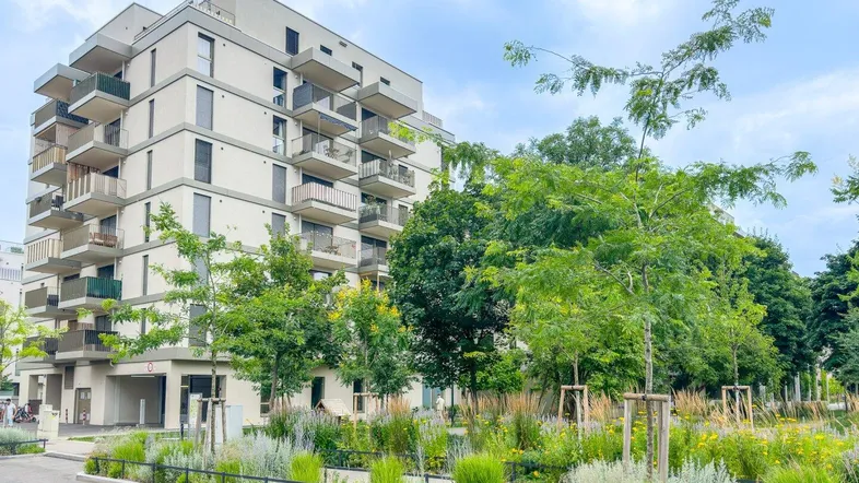 Modernes Apartmentgebäude mit zahlreichen Balkonen und einer ansprechend gestalteten Grünanlage.