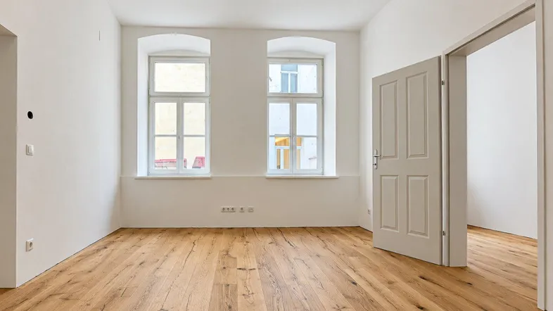Helles Zimmer mit neuem Holzboden und weißen Wänden, bereit zur individuellen Gestaltung.