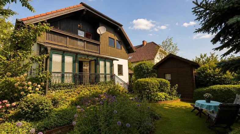 Charmantes Haus mit gepflegtem Garten, üppiger Bepflanzung und gemütlicher Sitzecke im Freien.