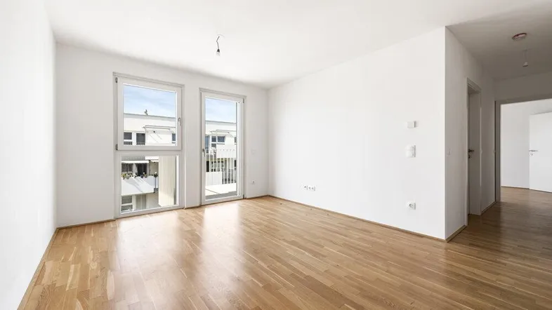 Helles Zimmer mit Parkettboden und Zugang zum Balkon, ideal als Wohnzimmer.