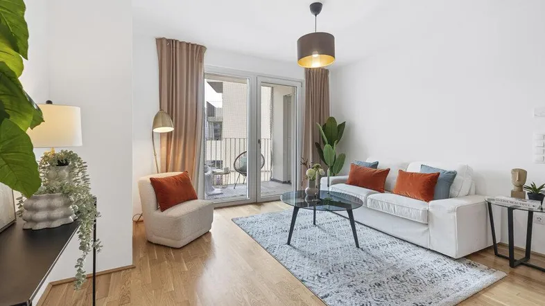 Helles Wohnzimmer mit Holzboden, modernem Teppich und Zugang zu einem Balkon.