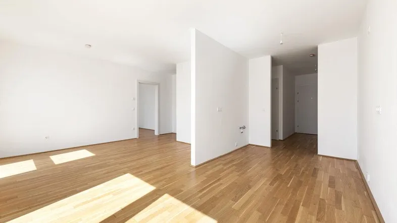 Helles, leeres Zimmer mit Parkettboden und viel Tageslicht, bereit zur individuellen Gestaltung.