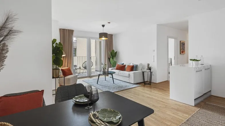 Heller, offener Wohn- und Essbereich mit Holzboden und Zugang zu einem Balkon.