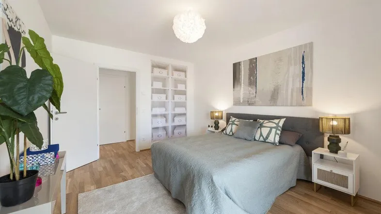 Helles Schlafzimmer mit Holzboden, einem Doppelbett und integrierten Wandschränken für Stauraum.