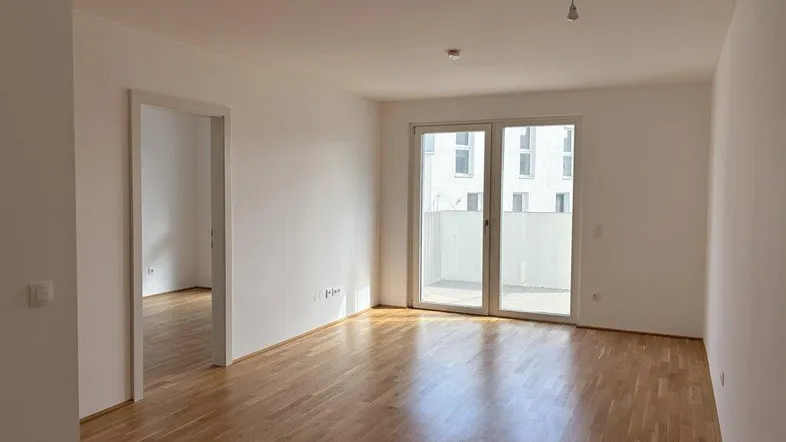 Helles Zimmer mit Parkettboden und Zugang zu einem Balkon, bereit für die individuelle Gestaltung.