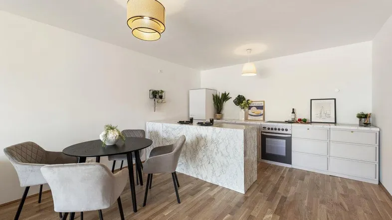 Helle, offene Küche mit moderner Marmorinsel, integrierten Geräten und Essbereich mit Holzboden.
