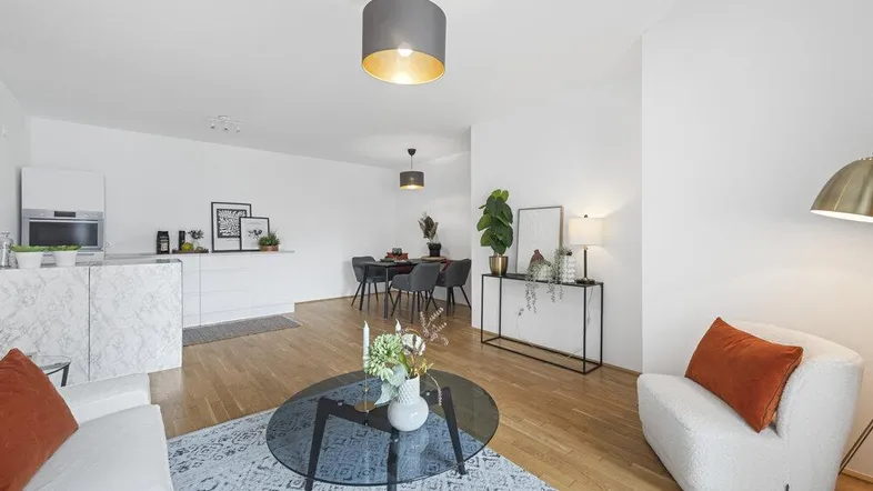 Helles, offenes Wohnzimmer mit integrierter Küche, Parkettboden und modernen Möbeln.