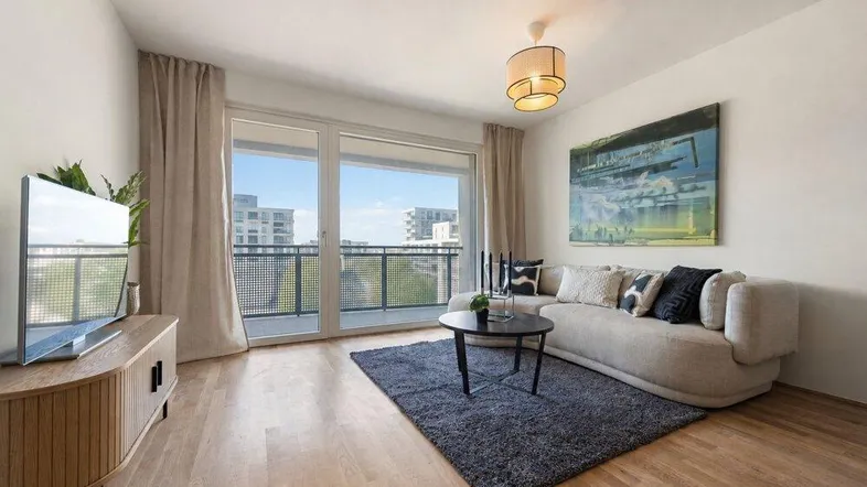 Helles Wohnzimmer mit Holzboden, modernem Sofa und Zugang zu einem Balkon mit Stadtblick.