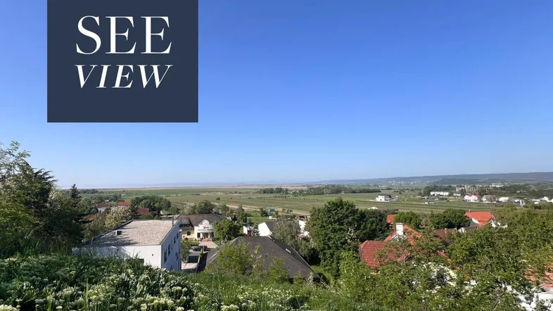 Panoramablick über eine weite Landschaft mit See im Hintergrund und umliegenden Häusern.
