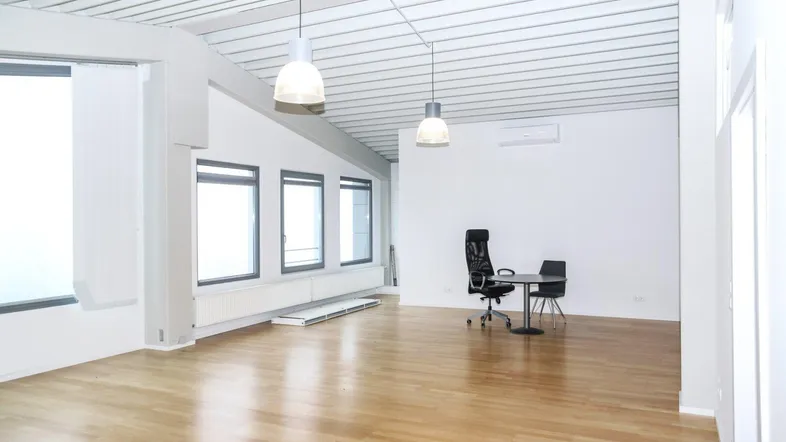 Geräumiges, helles Büro mit Holzboden, großen Fenstern und moderner Deckenverkleidung.