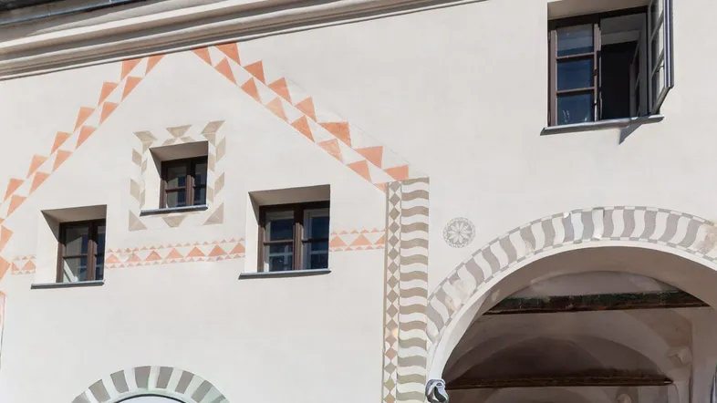 Fassade eines historischen Gebäudes mit traditionellen Mustern und Fenstern unter blauem Himmel.
