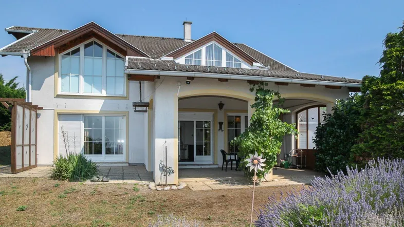 Hausfassade mit überdachter Terrasse, Sitzbereich und blühendem Lavendel im Vorgarten.