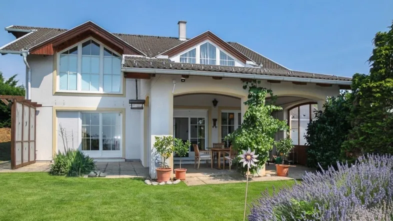 Großzügige Terrasse mit Gartenmöbeln und Blick auf den gepflegten Rasen und die blühenden Pflanzen.