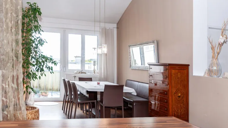 Helles Esszimmer mit großem Esstisch, bequemer Sitzbank und Zugang zum Balkon.