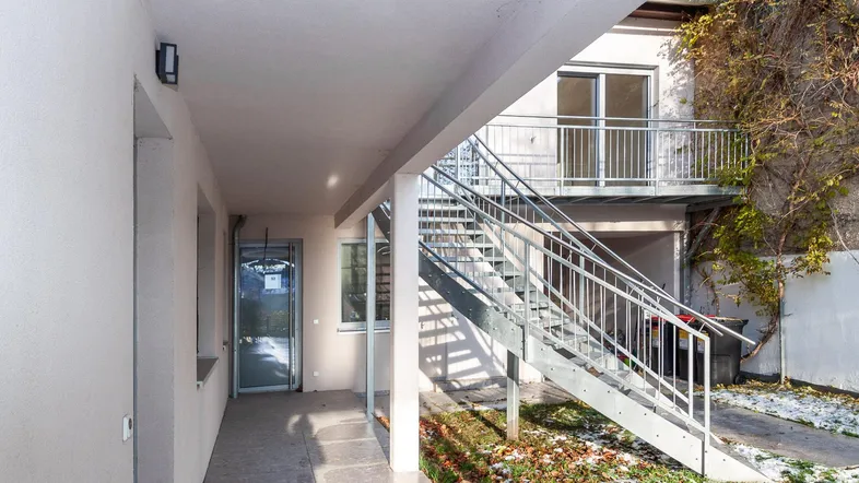 Außenansicht des Gebäudes mit einer Metalltreppe, die zu den oberen Etagen führt.