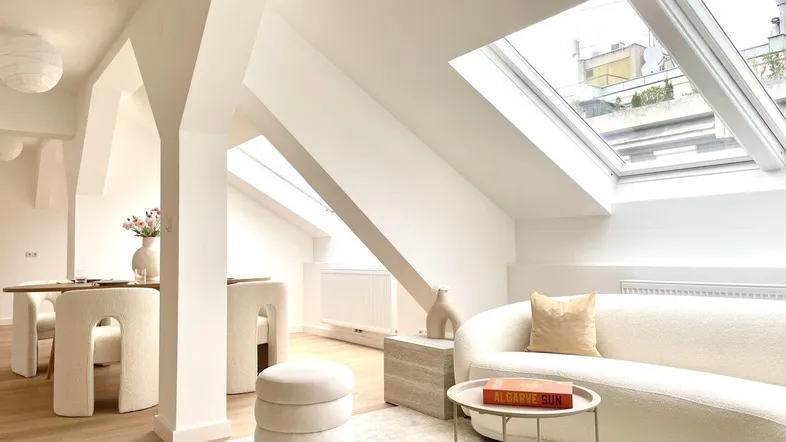 Helles Wohn- und Esszimmer mit Dachschrägen, modernen Möbeln und großen Dachfenstern.
