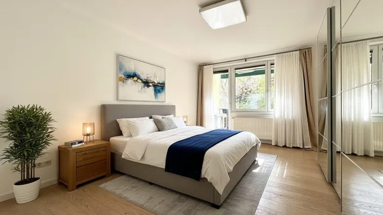Modernes Schlafzimmer mit hellem Parkettboden, großem Bett und Spiegelschrank.