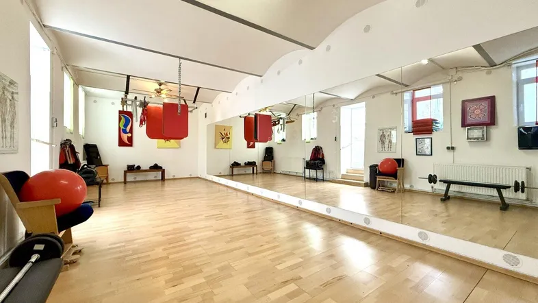 Geräumiger Fitnessraum mit Holzboden, großen Spiegeln und Boxsäcken, ideal für Trainingseinheiten.