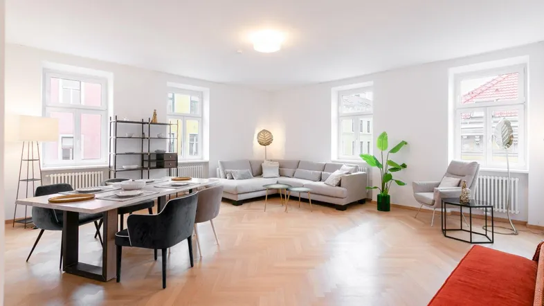 Helles Wohn- und Esszimmer mit Fischgrätparkett, modernen Möbeln und großen Fenstern.