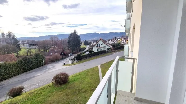 Balkon mit Glasgeländer bietet einen weiten Blick auf die umliegende Landschaft und Berge.