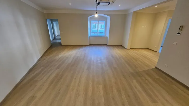 Geräumiger, heller Wohnbereich mit modernem Laminatboden und Klimaanlage an der Decke.