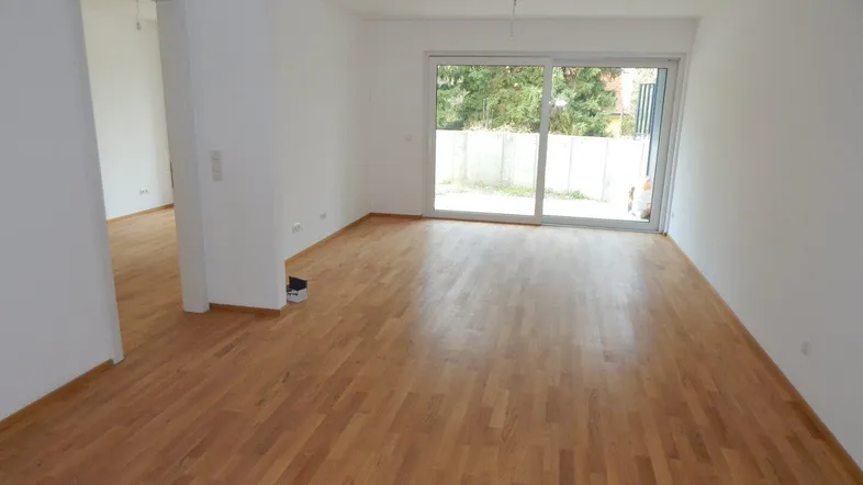 Helles Wohnzimmer mit Parkettboden und großen Schiebetüren zum Garten oder zur Terrasse.