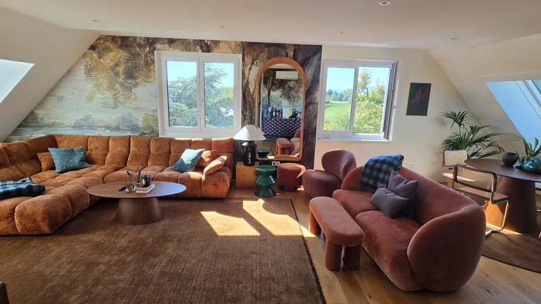 Geräumiger Wohn- und Essbereich mit gemütlichen Sofas, Holzboden und viel natürlichem Licht durch Dachfenster.