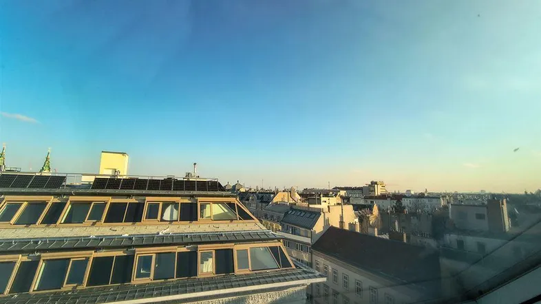 Panoramablick über die Dächer der Stadt mit blauem Himmel und modernen Solaranlagen auf einem Gebäude.