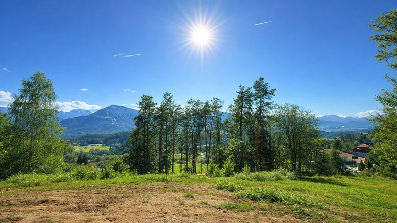 Panoramablick auf die majestätischen Berge und die grüne Landschaft unter strahlend blauem Himmel.
