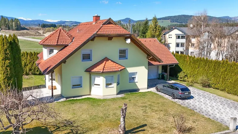 Freistehendes Einfamilienhaus mit gepflegtem Garten, Auffahrt und Bergblick in ländlicher Umgebung.