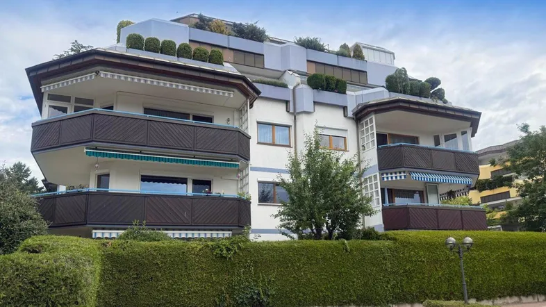 Mehrstöckiges Wohngebäude mit mehreren Balkonen und begrünten Dächern in moderner Architektur.