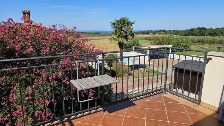 Geräumiger Balkon mit Meerblick, umgeben von blühenden Pflanzen und ländlicher Landschaft.