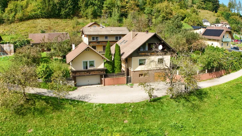 Ländliches Haus mit Satteldach und umgebender grüner Landschaft in sonniger Lage.