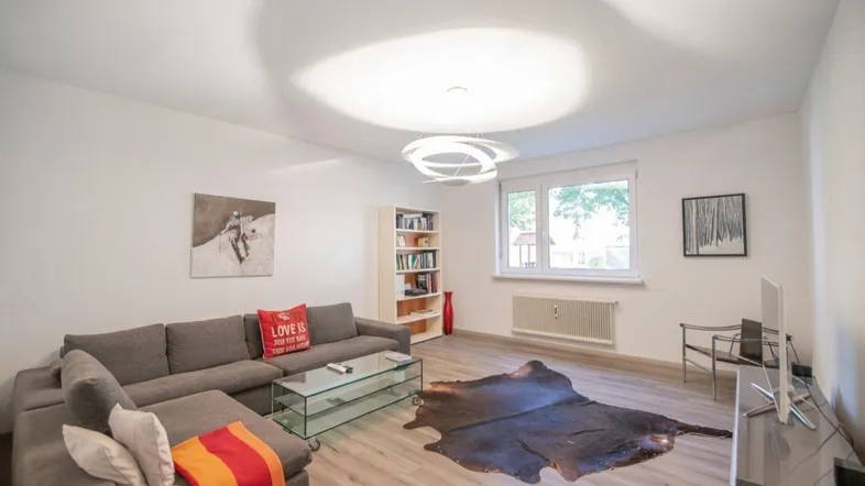 Helles Wohnzimmer mit modernem Sofa, Glas-Couchtisch und Laminatboden, ideal zum Entspannen.