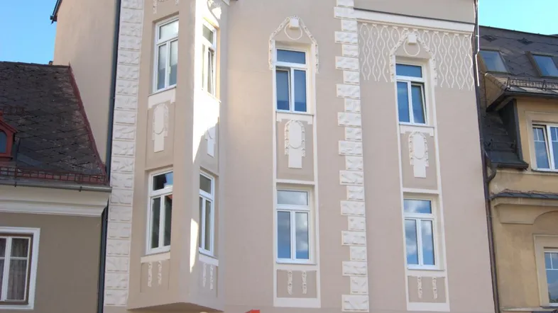 Die Fassade des Gebäudes zeigt einen Erker und dekorative Elemente, die dem Haus Charakter verleihen.