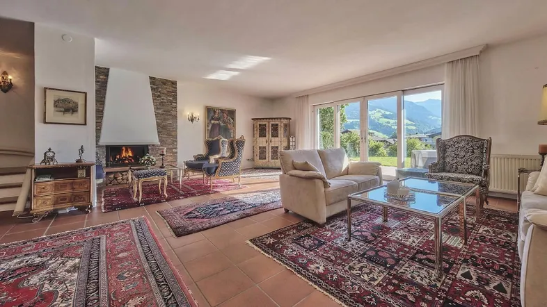 Geräumiges Wohnzimmer mit Kamin, bequemen Sofas und direktem Zugang zur Terrasse mit Bergblick.