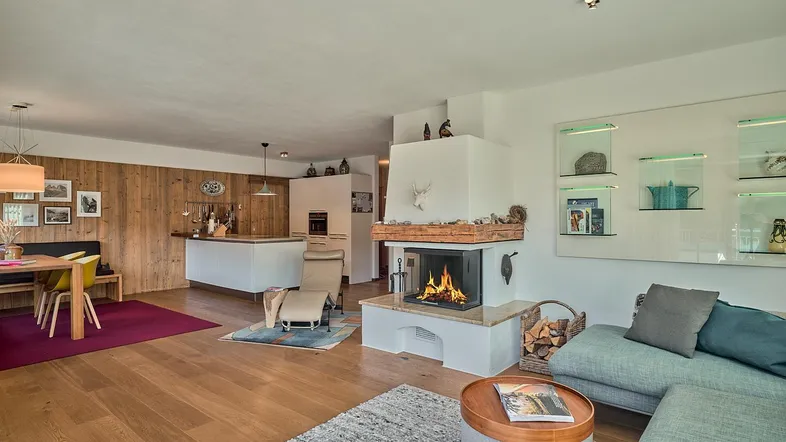 Geräumiger offener Wohn- und Essbereich mit Kamin, Holzboden und moderner Einrichtung.