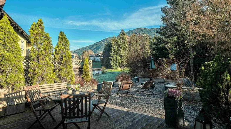 Geräumige Holzterrasse mit Sitzgelegenheiten und weitem Blick auf die umliegende Berglandschaft.