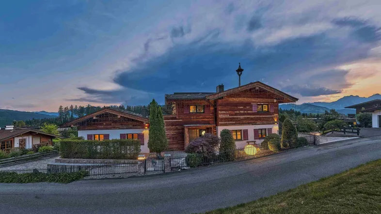 Charmantes Chalet-Anwesen in den Bergen bei Sonnenuntergang mit gepflegtem Garten und Auffahrt.