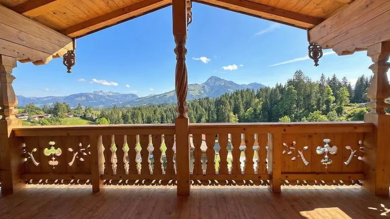 Geräumiger Holzbalkon mit kunstvoll geschnitztem Geländer und atemberaubendem Bergblick.
