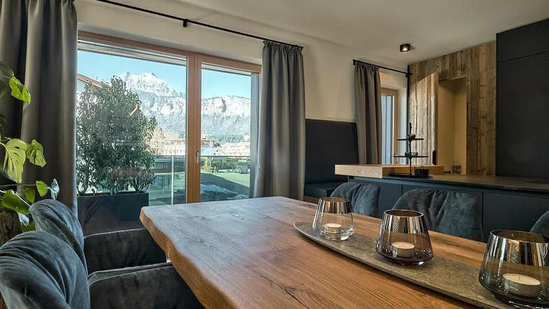 Heller Essbereich mit rustikalem Holztisch, bequemen Stühlen und beeindruckendem Bergblick.