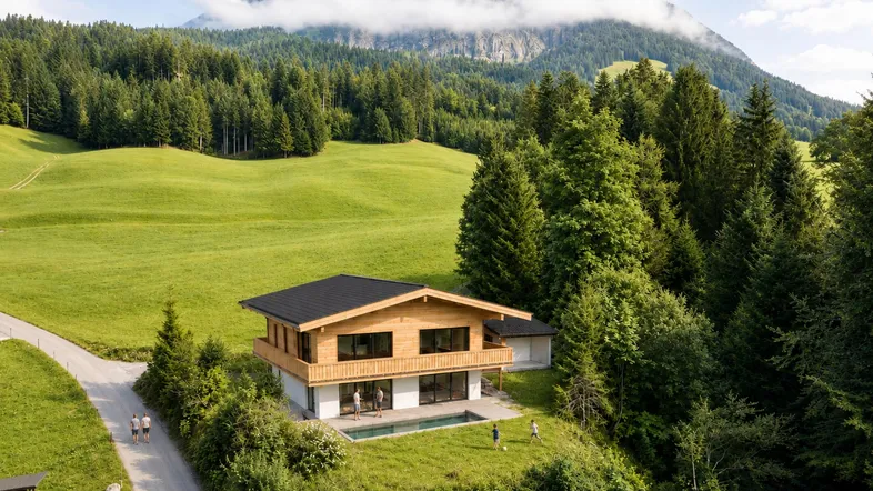 Modernes Holzhaus mit Flachdach und kleinem Pool in alpiner Landschaft mit Bergblick.