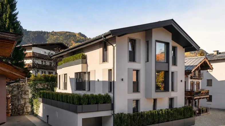 Moderne Architektur mit klaren Linien und begrünten Terrassen in alpiner Umgebung.